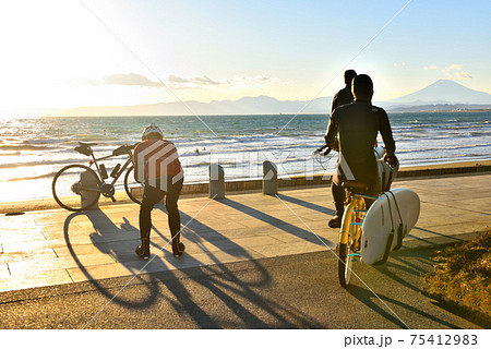 西日を浴びて影が長く伸びるサイクリスト 75412983