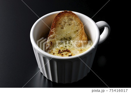 カップで食べるオニオングラタンスープを黒背景で撮影 75416017