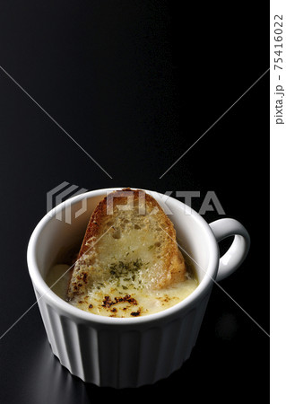 カップで食べるオニオングラタンスープを黒背景で撮影 75416022