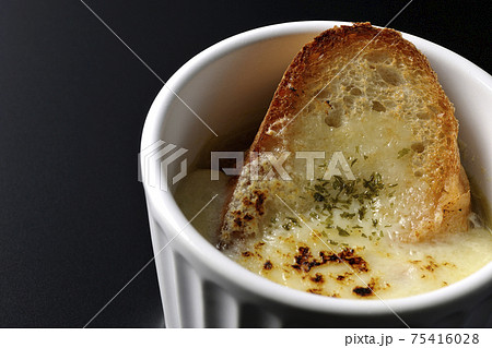 カップで食べるオニオングラタンスープを黒背景で撮影 75416028