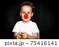 Boy with a clown red nose and red noses in hands. Red Nose Day. 75416141