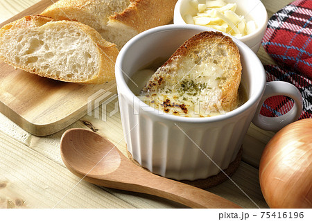 オニオングラタンスープのまわりにフランスパン、チーズ、スプーン、玉葱、ミトン オニオングラタンスープのまわりにフランスパン、チーズ、スプーン、玉葱、ミトン 75416196