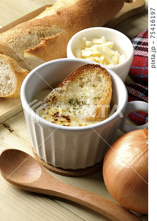 オニオングラタンスープのまわりにフランスパン、チーズ、スプーン、玉葱、ミトン オニオングラタンスープのまわりにフランスパン、チーズ、スプーン、玉葱、ミトン 75416197
