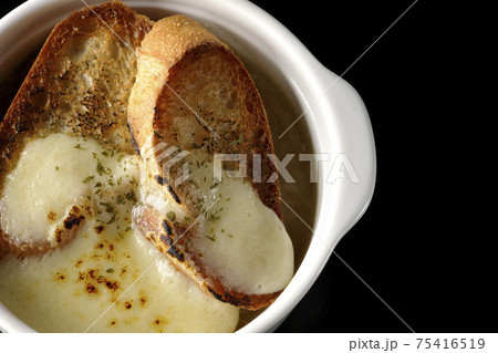焦げ目のついたチーズ、フランスパンが入ってるオニオンスープを黒背景で撮影(俯瞰) 焦げ目のついたチーズ、フランスパンが入ってるオニオンスープを黒背景で撮影(俯瞰) 75416519