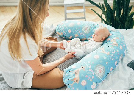 Young mother with baby in bed with a pillow for pregnant women. Young mother with baby in bed with a pillow for pregnant women. 75417033