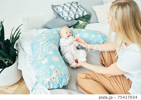 Young mother with baby in bed with a pillow for pregnant women. Young mother with baby in bed with a pillow for pregnant women. 75417034