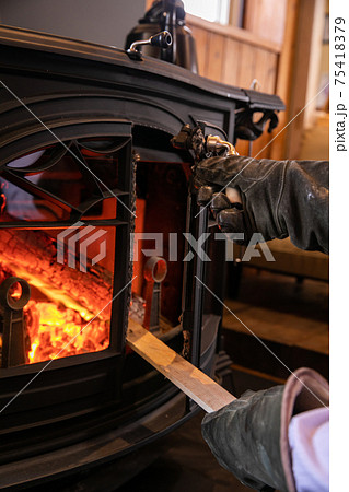薪ストーブ（暖炉）に薪をくべる写真 75418379