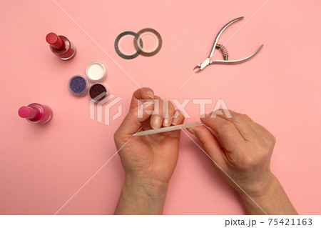 Woman Hands Filing Nails. Gives himself a manicure. Elderly hands. Pink background. Woman Hands Filing Nails. Gives himself a manicure. Elderly hands. Pink background. 75421163