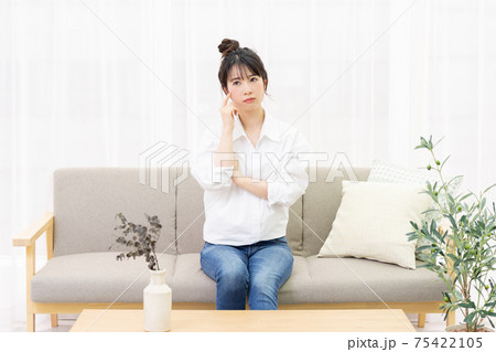 窓際のソファに座って考え事をする若い女性 窓際のソファに座って考え事をする若い女性 75422105