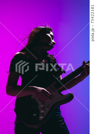 Silhouette of young female guitarist isolated on gradient background in neon. 75422181