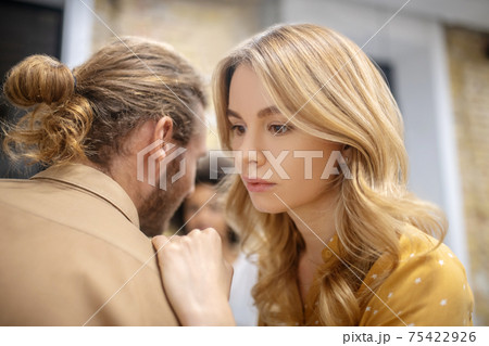A girl sharing her secrets on the ear to her friend 75422926