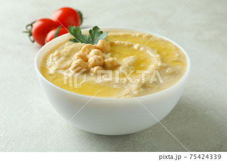 Bowl of hummus and tomatoes on white textured background 75424339