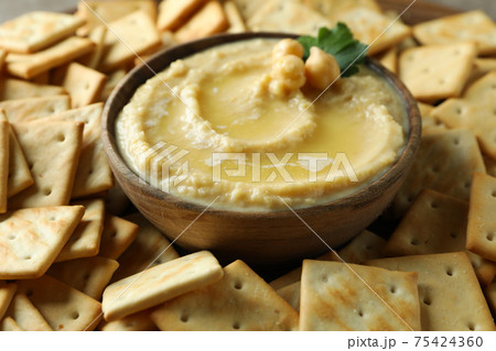 Bowl of hummus on crackers background, close up Bowl of hummus on crackers background, close up 75424360