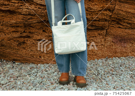 Young woman hold stylish eco bag outdoor against big sea stone Young woman hold stylish eco bag outdoor against big sea stone 75425067