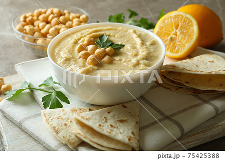 Concept of tasty eat with bowl of hummus on gray background Concept of tasty eat with bowl of hummus on gray background 75425388