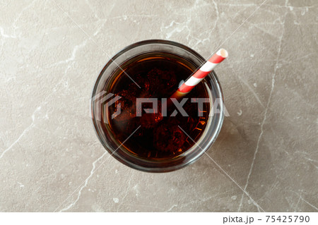 Glass of cola with ice cubes and straw on gray table Glass of cola with ice cubes and straw on gray table 75425790