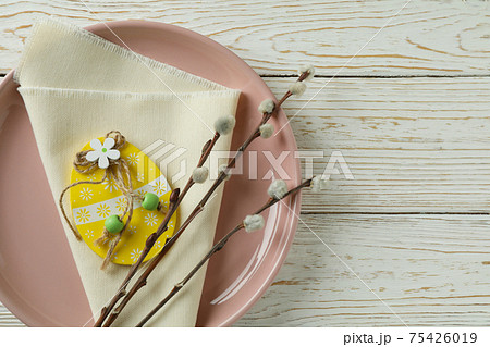 Plate with wooden Easter egg, kitchen napkin and catkins on wooden background Plate with wooden Easter egg, kitchen napkin and catkins on wooden background 75426019