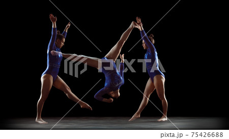 Young flexible girl on black studio background in strobe and neon light. Young female model practicing artistic gymnastics. Young flexible girl on black studio background in strobe and neon light. Young female model practicing artistic gymnastics. 75426688