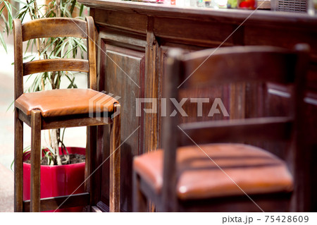 brown wood bar stool with high legs and leather seat cushion at the pub bar in retro style close-up of seat details, nobody. brown wood bar stool with high legs and leather seat cushion at the pub bar in retro style close-up of seat details, nobody. 75428609