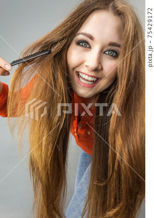 Woman combing her brown hair Woman combing her brown hair 75429172