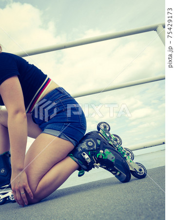 Woman putting roller skates on Woman putting roller skates on 75429173