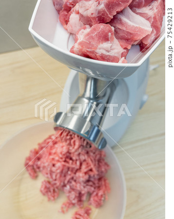 Meat grinder grinds pork meat 75429213
