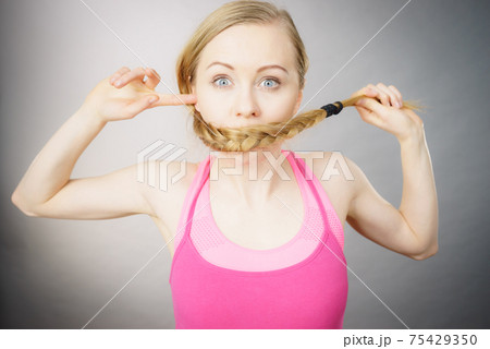 Woman covering her mouth with blonde braid Woman covering her mouth with blonde braid 75429350