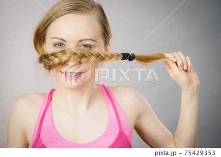 Woman covering her mouth with blonde braid 75429353