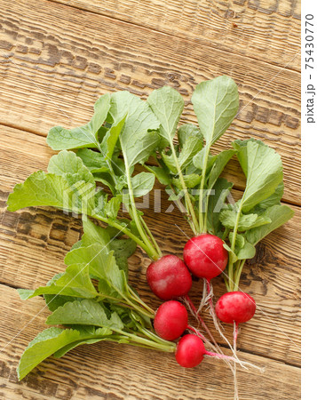 Ripe red radishes with green leaves on wooden boards. 75430770