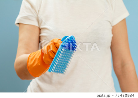 Woman holding a plastic brush on a blue background. Woman holding a plastic brush on a blue background. 75430934