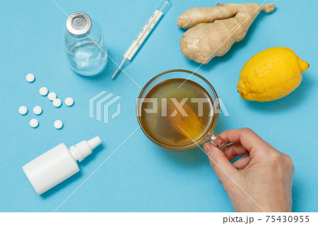 Female hand with a cup of tea and health remedy foods for cold and flu relief. 75430955