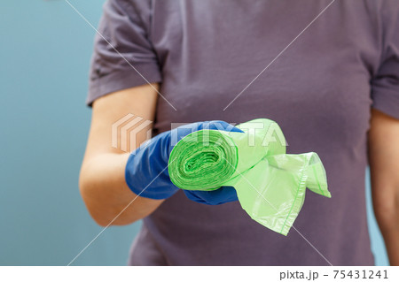 Woman holding garbage bags on a blue background. 75431241