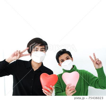 Two Asian woman friends wearing mask with heart balloon support and encourage people form Covid-19 pandemic 75436023
