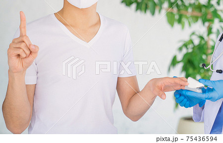 パルスオキシメーターでサチュレーション測定をしながら指差す男性患者 75436594