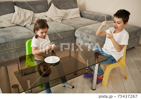 Children, boy and girl, coloring Easter eggs at home. High angle view 75437267