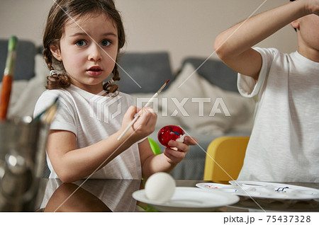 Easter, family, holiday and child concept . Cute little girl coloring eggs for Easter Easter, family, holiday and child concept . Cute little girl coloring eggs for Easter 75437328