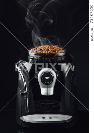 fresh roasted coffee beans with smoke in coffeemaker bean container, close-up view 75437650