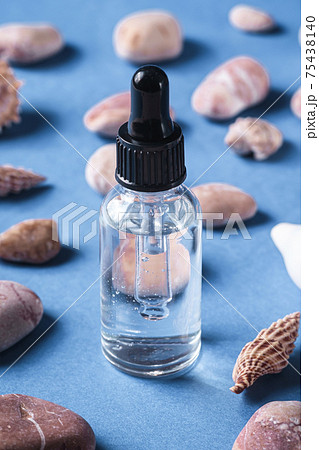 Skin care essence oil dropper in glass bottle near to seashells and pebbles 75438140