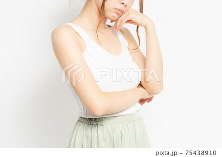 白背景の前に立って考え事をする若い女性 75438910