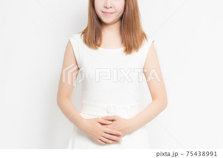 白背景の前に立って、お腹に手を当てている女性 75438991