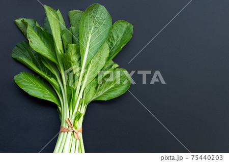 Fresh choy Sum on dark background. 75440203
