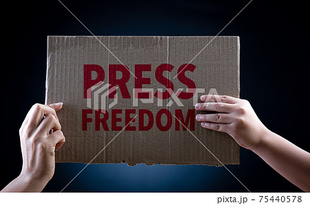 World press freedom day concept. Hand holding cardboard paper with the text on dark background, conceptual image, symbol of press or speech freedom. World press freedom day concept. Hand holding cardboard paper with the text on dark background, conceptual image, symbol of press or speech freedom. 75440578