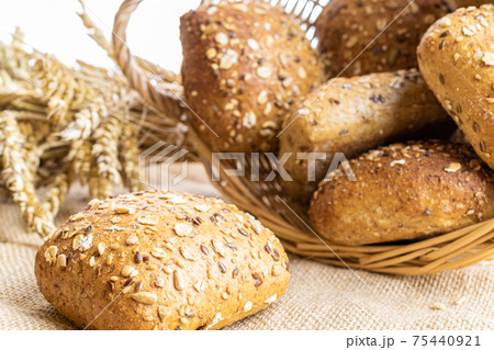Rye bread. Bakery with crusty loaves and crumbs. Fresh loaf of rustic traditional bread with wheat grain ear or rye spike plant on natural cotton background. Healthy Food concept. Rye bread. Bakery with crusty loaves and crumbs. Fresh loaf of rustic traditional bread with wheat grain ear or rye spike plant on natural cotton background. Healthy Food concept. 75440921