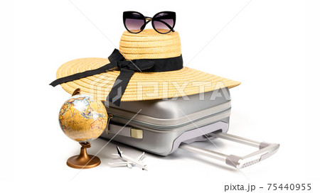 Tropical background. Suitcase, sunglasses with toy plane, straw hat and globe in travel composition isolated on white background. Exotic tropical beach with copy space. 75440955