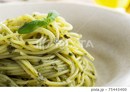 ナチュラルな背景で撮影された、バジルソースのスパゲティー 75443400