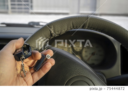 empty, dead battery and car alarm keychain in the car driver's hand 75444872