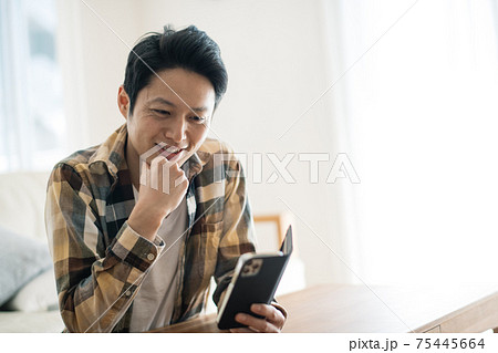 笑顔でスマホを見る男性 75445664