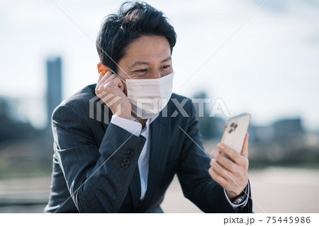 スマホを見るマスクをしたビジネスマン スマホを見るマスクをしたビジネスマン 75445986