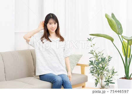 部屋のソファーに座って聞き耳を立てる若い女性 部屋のソファーに座って聞き耳を立てる若い女性 75446597