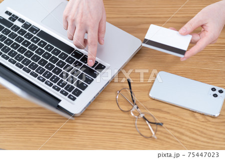ネットショッピング　パソコンにクレジットカード情報を入力しようとするシニア女性の手元 75447023